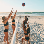 A group of people playing volleyball at a beach