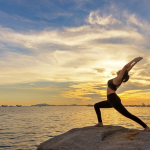 person stretching their arms near a body of water