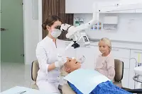 Screenshot 2023-08-03 at 17-22-46 Premium Photo A blond woman having her teeth checked at the dentist's office with her daughter waiting for her