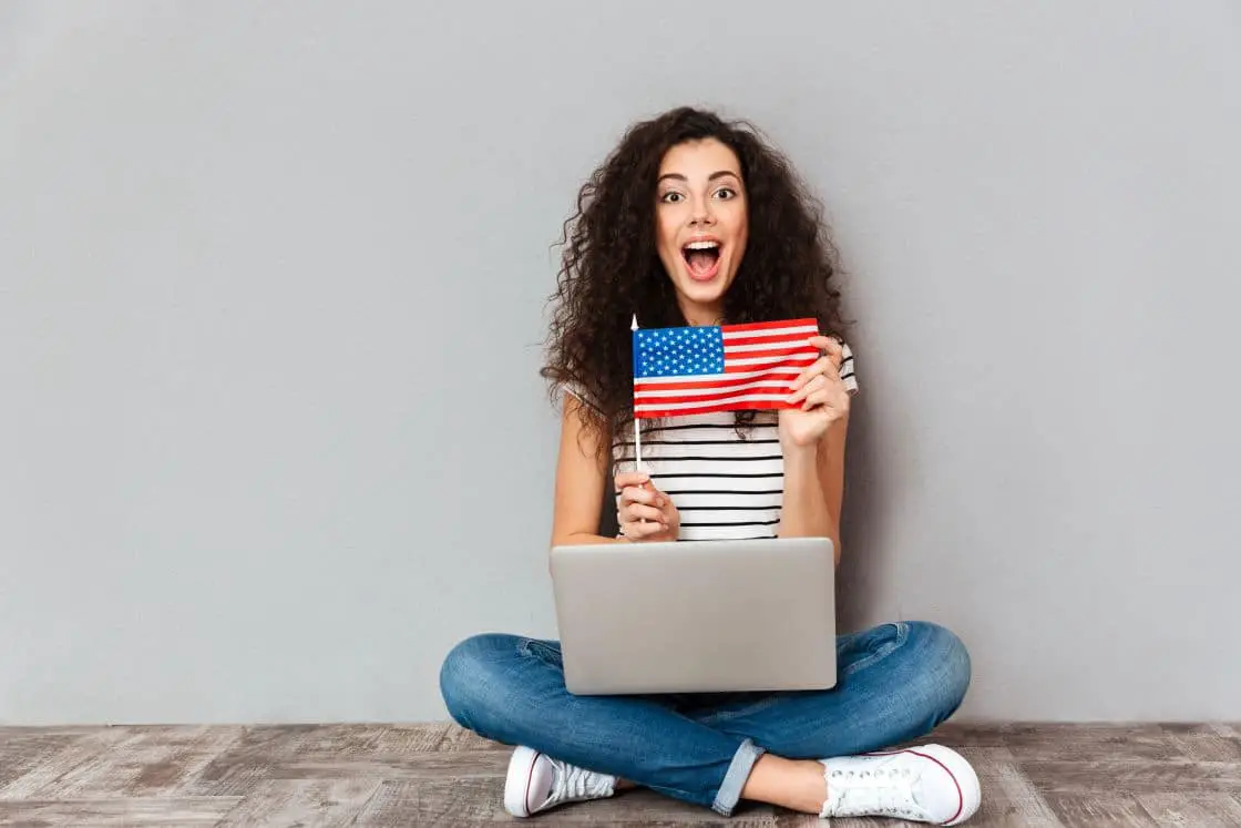 gorgeous-female-with-beautiful-smile-sitting-lotus-pose-with-silver-computer-legs-demonstrating-american-flag-grey-wall1