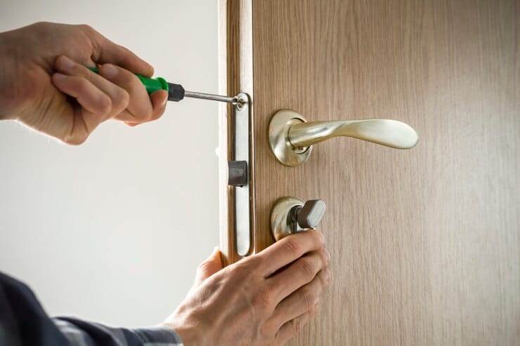 carpenter-repairs-door-lock-installation-door-handle-with-tool_8119-2109