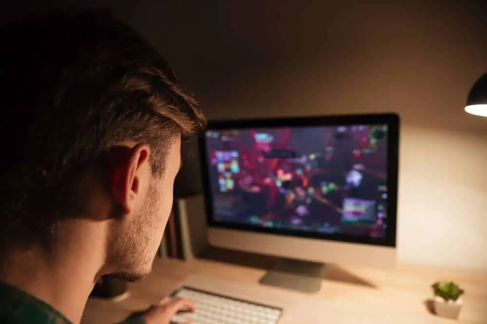 closeup-of-young-man-playing-computer-games-at-the-table-in-the-evening-SBI-302849212