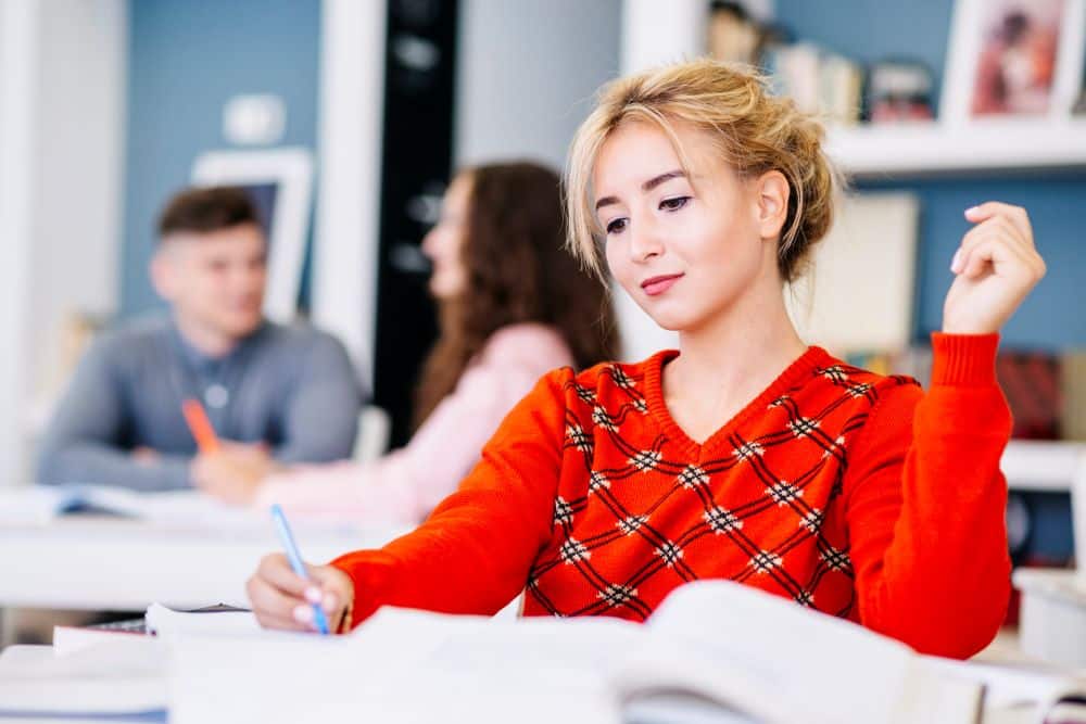 young-female-writing-textbook-library1