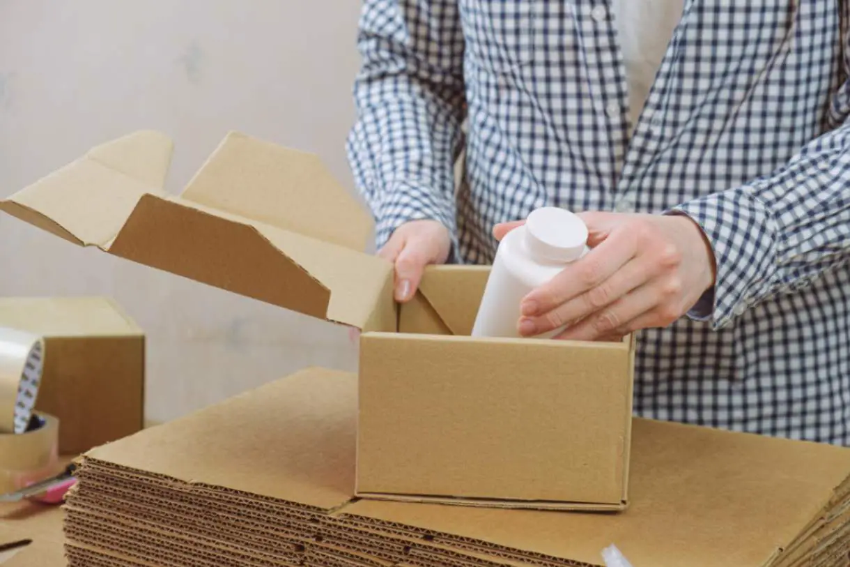 jpeg-optimizer_woman-warehouse-is-packing-plastic-jar-with-vitamins-cardboard-box
