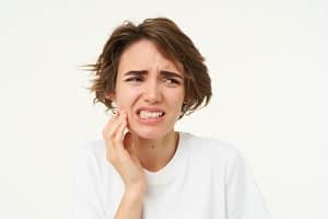 close-up-woman-has-toothache-touches-her-teeth-frowns-from-painful-discomfort-stands