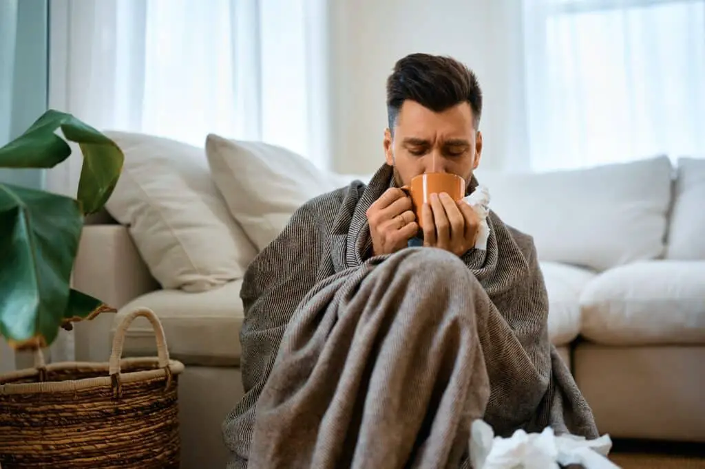 sick-man-wrapped-in-blanket-drinking-tea-at-home--1024x682