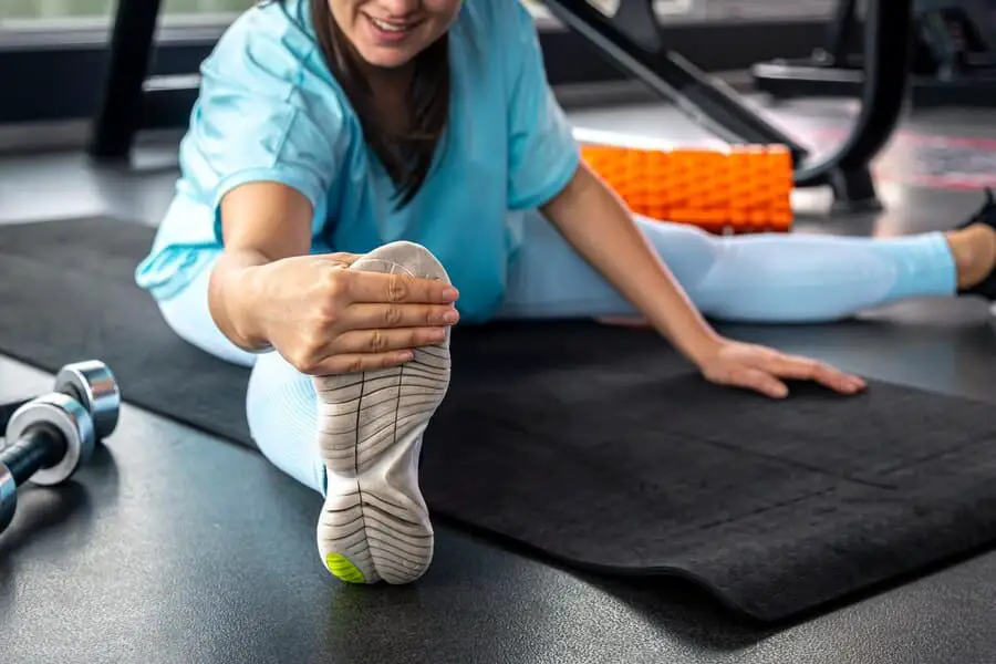 woman-stretching-legs-exercise-mat-before-training-gym_169016-47260